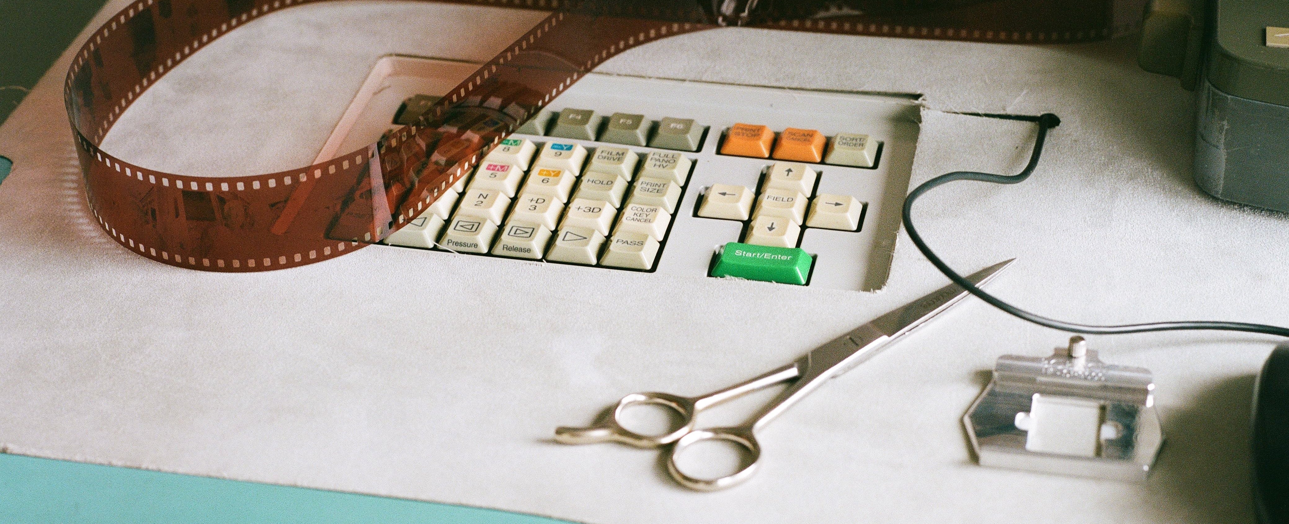 Desk with film reel, scissors, and other items on a white surface