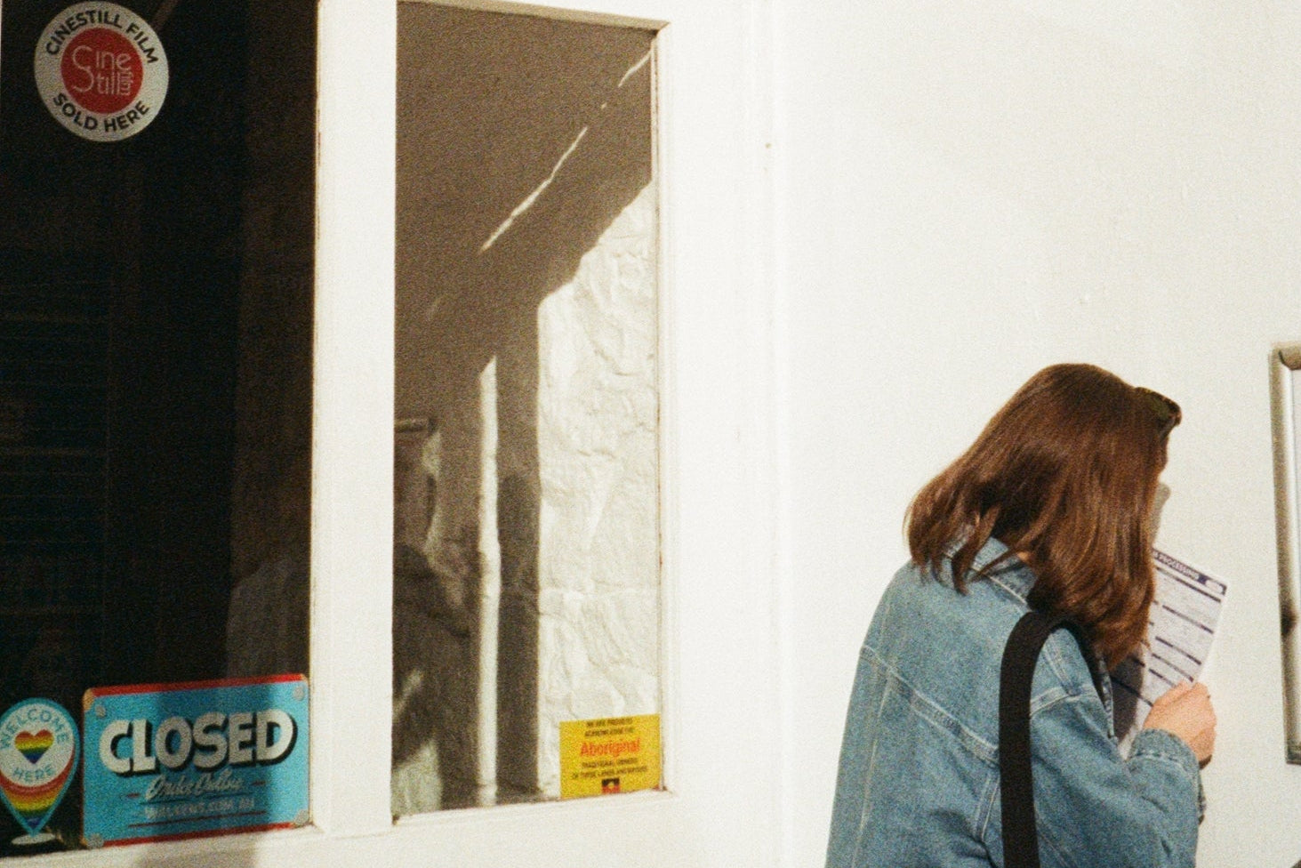 Person leaning over a door with a 'Kodak' sign above, indicating a photo processing lab.